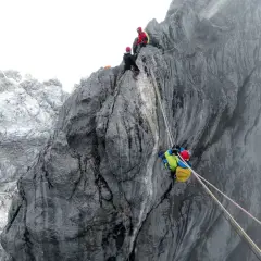 Wspinaczka na Piramidę Carstensza. Alpinisci zmagają się z trudnym terenem, używając lin do pokonania stromych ścian.