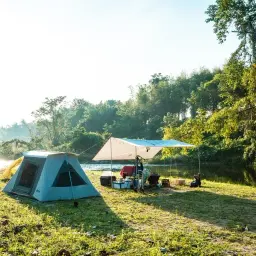 Idealne miejsce, gdzie pod namiot nad jezioro. Poranek nad wodą, zieleń, spokój i gotowość do wypoczynku.