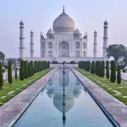 Majestatyczny Taj Mahal odbija się w spokojnej wodzie, otoczony geometrycznymi ogrodami i strzelistymi cyprysami.