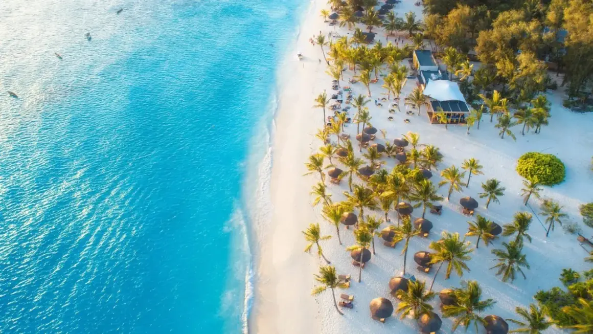 Rajska plaża na Zanzibarze, z turkusową wodą i palmami. Nawet podczas pory deszczowej Zanzibar zachwyca pięknem.