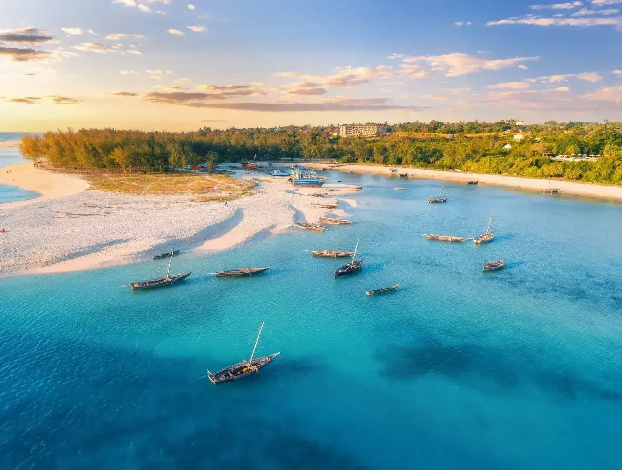 Zanzibar pora deszczowa. Spokojna, turkusowa woda, piaszczysta plaża i łodzie czekające na odpłynięcie.